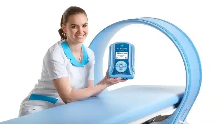 מטפלת עם יחידת הבקרה של Biomag Lumina 3D-e ליד מיטת טיפולים עם אפליקטור מגנטי